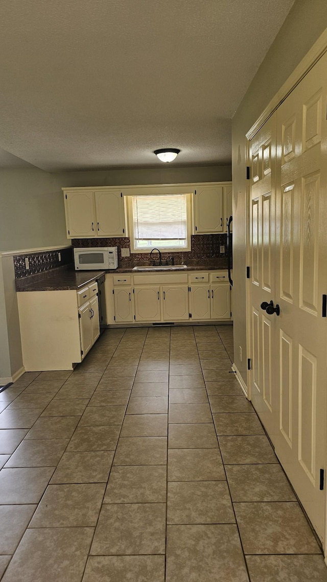 1949 Timberline Cir, Oak Grove, KY 42262 - kitchen with dark countertops, white microwave, dark tile patterned flooring, white cabinets, and a textured ceiling