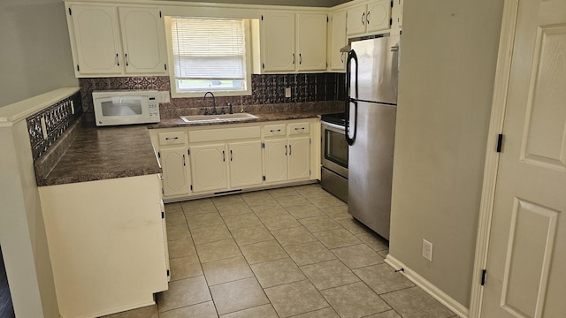 1949 Timberline Cir, Oak Grove, KY 42262 - kitchen featuring appliances with stainless steel finishes, dark countertops, light tile patterned floors, and tasteful backsplash