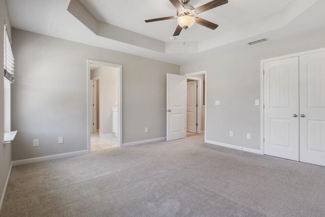 215 Ruth Way, Spring Hill, TN 37174 - unfurnished bedroom featuring a raised ceiling, light carpet, a closet, connected bathroom, and a ceiling fan