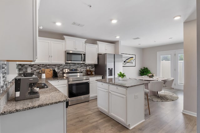 215 Ruth Way, Spring Hill, TN 37174 - kitchen with stainless steel appliances, tasteful backsplash, light wood-style flooring, a kitchen island, and recessed lighting