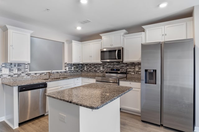 215 Ruth Way, Spring Hill, TN 37174 - kitchen featuring appliances with stainless steel finishes, white cabinetry, light wood-style floors, a kitchen island, and backsplash