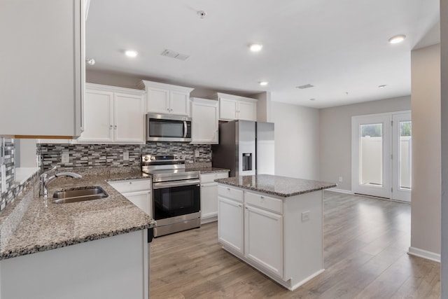 215 Ruth Way, Spring Hill, TN 37174 - kitchen featuring appliances with stainless steel finishes, backsplash, light wood-type flooring, a kitchen island, and stone countertops