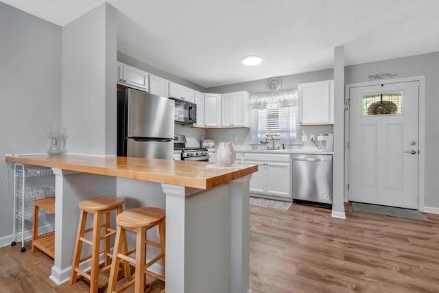 109 Saint Margarett Cir, Columbia, TN 38401 - kitchen with stainless steel appliances, a breakfast bar, white cabinets, light wood-style floors, and wooden counters