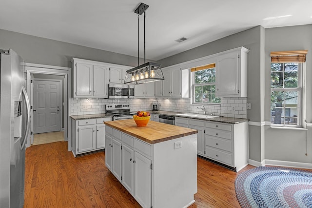 205 Seneca Ct, Franklin, TN 37067 - kitchen with appliances with stainless steel finishes, wood counters, wood finished floors, white cabinets, and decorative backsplash