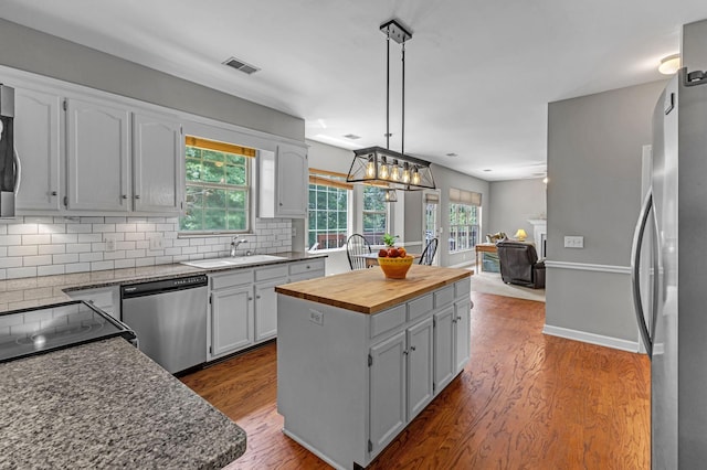 205 Seneca Ct, Franklin, TN 37067 - kitchen with stainless steel appliances, butcher block countertops, a kitchen island, backsplash, and dark wood-style floors