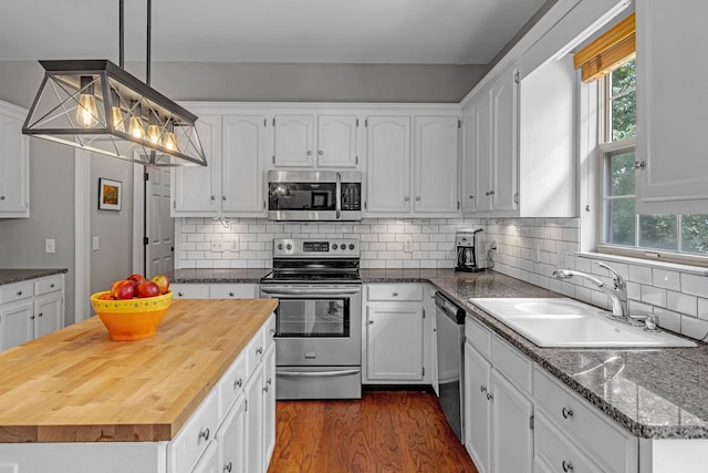 205 Seneca Ct, Franklin, TN 37067 - kitchen featuring stainless steel appliances, butcher block counters, white cabinets, dark wood-type flooring, and decorative light fixtures