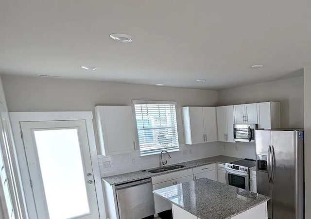 4234 Gandalf Ln, Murfreesboro, TN 37128 - kitchen featuring appliances with stainless steel finishes, a kitchen island, white cabinetry, backsplash, and light stone counters