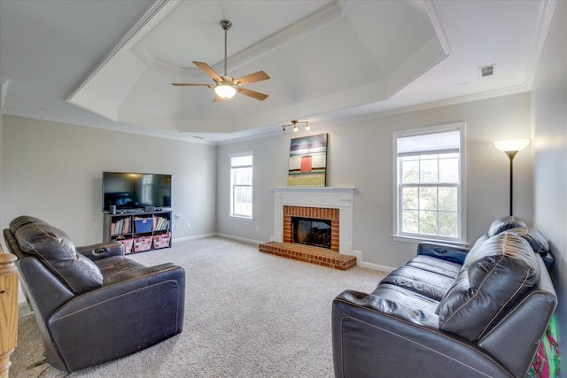 1301 Saybrook Xing, Thompsons Station, TN 37179 - carpeted living room featuring a raised ceiling, ornamental molding, ceiling fan, and a brick fireplace