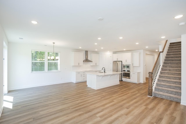 137 W Cassa Way, Mount Juliet, TN 37122 - kitchen featuring stainless steel appliances, wall chimney range hood, light countertops, a kitchen bar, and light wood-type flooring