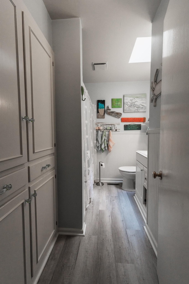 818 W Clark Blvd, Murfreesboro, TN 37129 - bathroom featuring wood finished floors, a skylight, vanity, wainscoting, and a shower with shower curtain