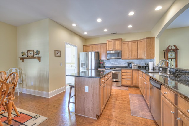 154 Salient Ln, Mount Juliet, TN 37122 - kitchen featuring stainless steel appliances, arched walkways, a kitchen breakfast bar, light wood finished floors, and backsplash