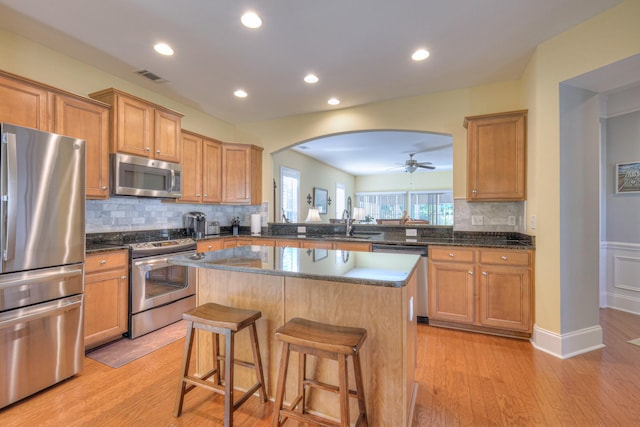 154 Salient Ln, Mount Juliet, TN 37122 - kitchen with stainless steel appliances, a center island, a breakfast bar area, decorative backsplash, and light wood-style flooring