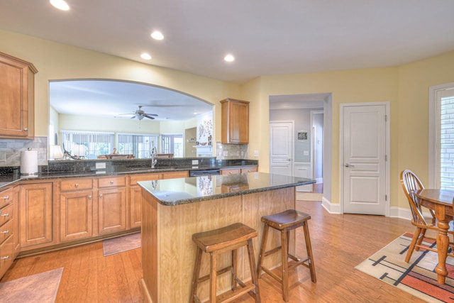 154 Salient Ln, Mount Juliet, TN 37122 - kitchen featuring light wood-style flooring, arched walkways, tasteful backsplash, a breakfast bar area, and a center island