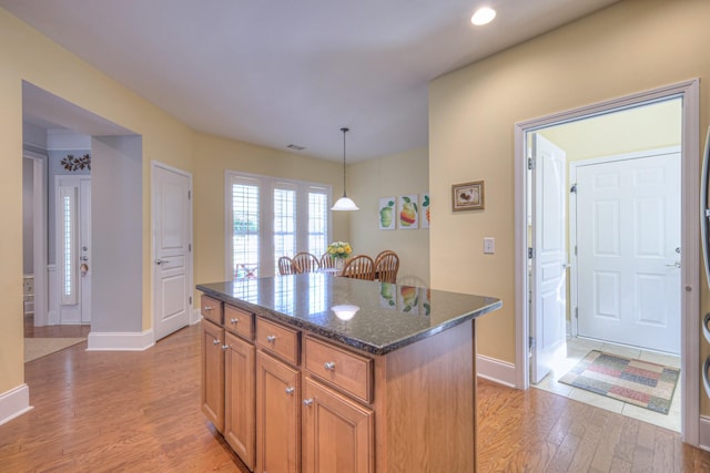 154 Salient Ln, Mount Juliet, TN 37122 - kitchen with light wood-type flooring, a kitchen island, dark stone counters, brown cabinets, and pendant lighting