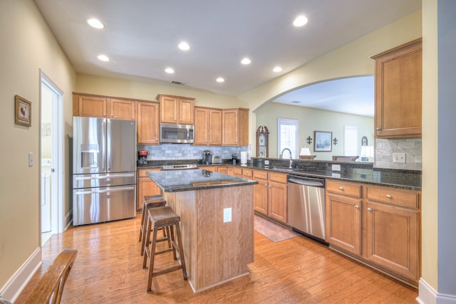 154 Salient Ln, Mount Juliet, TN 37122 - kitchen featuring stainless steel appliances, arched walkways, a center island, a breakfast bar, and decorative backsplash