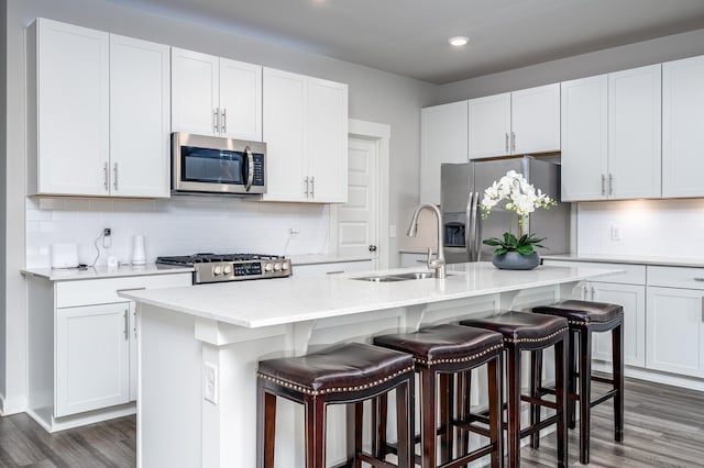 1013 Violet St, Spring Hill, TN 37174 - kitchen featuring appliances with stainless steel finishes, dark wood-style floors, an island with sink, white cabinetry, and tasteful backsplash