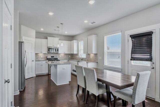 4905 Kingdom Dr, Murfreesboro, TN 37128 - kitchen with appliances with stainless steel finishes, a center island, tasteful backsplash, dark wood finished floors, and white cabinetry