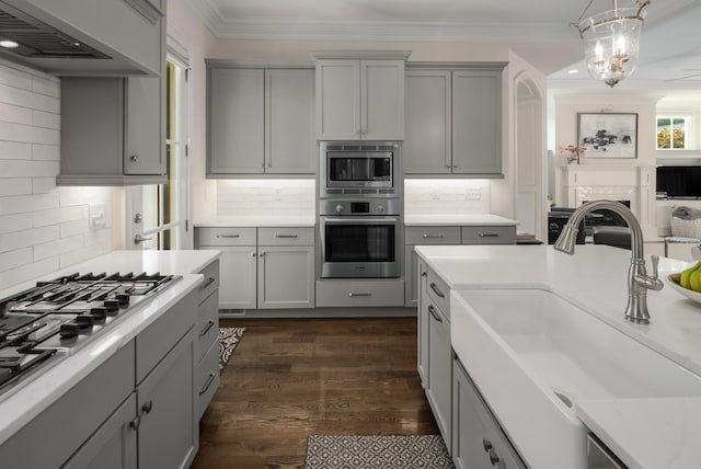 1450 Championship Blvd, Franklin, TN 37064 - kitchen featuring gray cabinetry, appliances with stainless steel finishes, exhaust hood, decorative backsplash, and ornamental molding