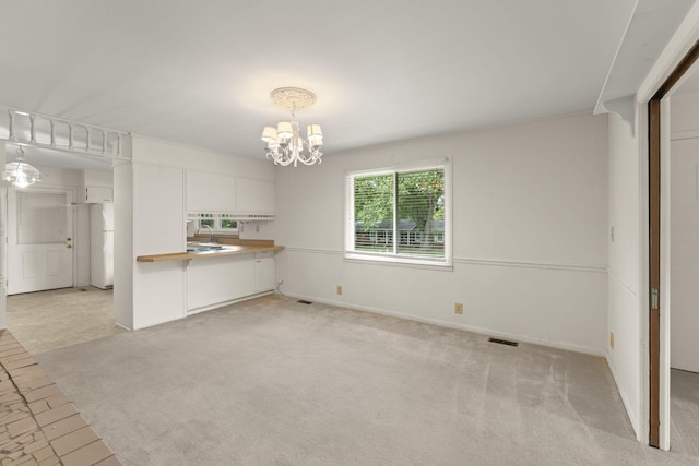 307 Mary Sharp Dr, Decherd, TN 37324 - kitchen with a chandelier, light colored carpet, white cabinetry, freestanding refrigerator, and decorative light fixtures