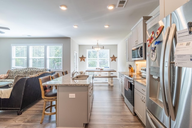 135 Millers Ln, Calhoun, GA 30701 - kitchen with stainless steel appliances, a kitchen bar, light stone countertops, a center island with sink, and dark wood-style flooring