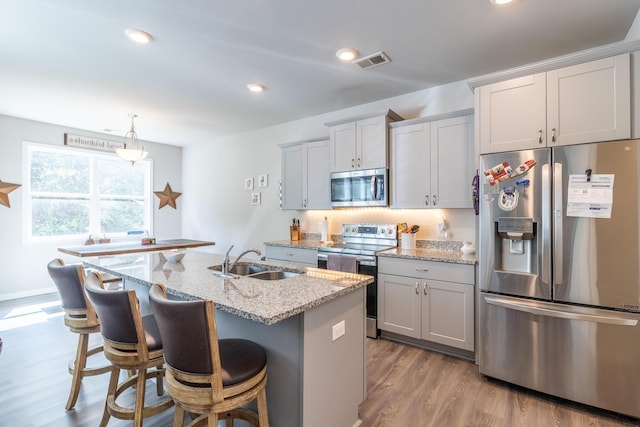 135 Millers Ln, Calhoun, GA 30701 - kitchen featuring appliances with stainless steel finishes, a breakfast bar, wood finished floors, light stone counters, and an island with sink