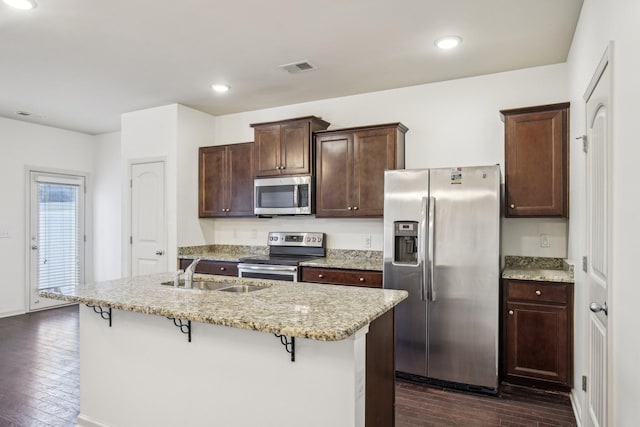 3927 Cannonsgate Ln, Murfreesboro, TN 37128 - kitchen featuring appliances with stainless steel finishes, dark wood finished floors, a breakfast bar, dark brown cabinetry, and a center island with sink