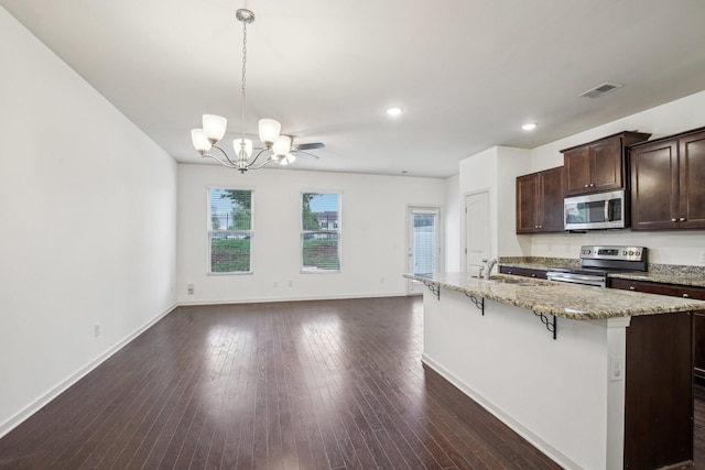 3927 Cannonsgate Ln, Murfreesboro, TN 37128 - kitchen with appliances with stainless steel finishes, a chandelier, dark brown cabinetry, a kitchen breakfast bar, and light stone countertops