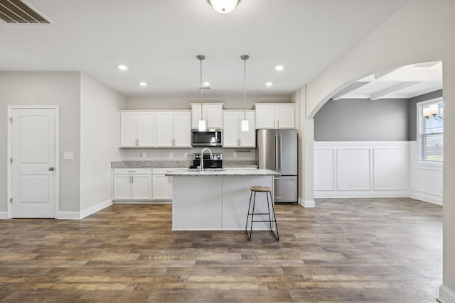 2237 Pathfinder Dr, Murfreesboro, TN 37127 - kitchen with arched walkways, an island with sink, appliances with stainless steel finishes, white cabinets, and dark wood finished floors