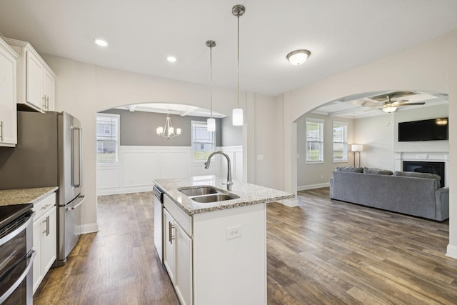 2237 Pathfinder Dr, Murfreesboro, TN 37127 - kitchen featuring arched walkways, ceiling fan, dark wood-type flooring, light stone counters, and a wainscoted wall