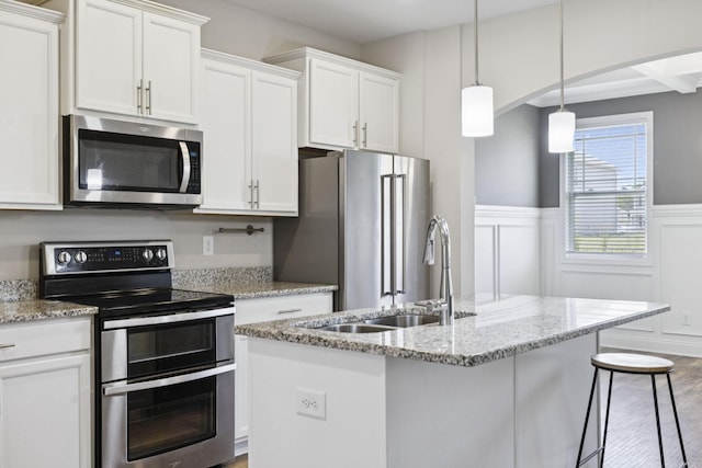 2237 Pathfinder Dr, Murfreesboro, TN 37127 - kitchen with appliances with stainless steel finishes, white cabinetry, wainscoting, wood finished floors, and a center island with sink