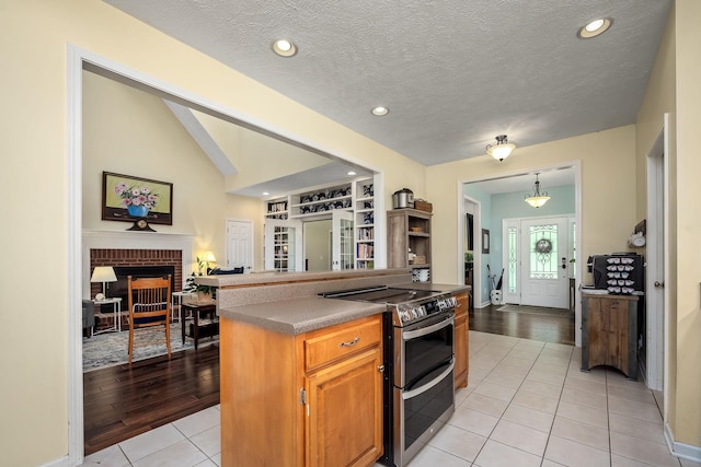 702 John Windrow Rd, Eagleville, TN 37060 - kitchen featuring double oven range, light tile patterned floors, open floor plan, dark countertops, and a brick fireplace