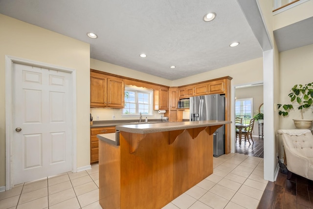 702 John Windrow Rd, Eagleville, TN 37060 - kitchen featuring appliances with stainless steel finishes, light tile patterned floors, a kitchen bar, brown cabinetry, and recessed lighting