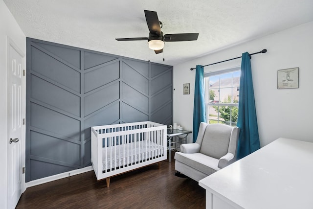 4826 Chelanie Cir, Murfreesboro, TN 37129 - bedroom with dark wood-style flooring, a textured ceiling, a crib, ceiling fan, and a decorative wall