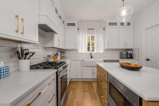 720 N Wickshire Way, Brentwood, TN 37027 - kitchen with stainless steel appliances, light wood-style flooring, custom exhaust hood, light countertops, and white cabinetry