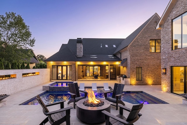 8524 Heirloom Blvd, College Grove, TN 37046 - rear view of property featuring an outdoor fire pit, a chimney, brick siding, a patio area, and a pool with connected hot tub