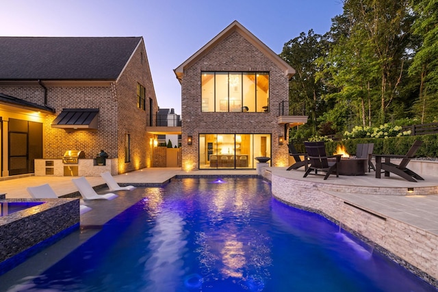 8524 Heirloom Blvd, College Grove, TN 37046 - back of property at dusk with an outdoor fire pit, exterior kitchen, brick siding, and a patio