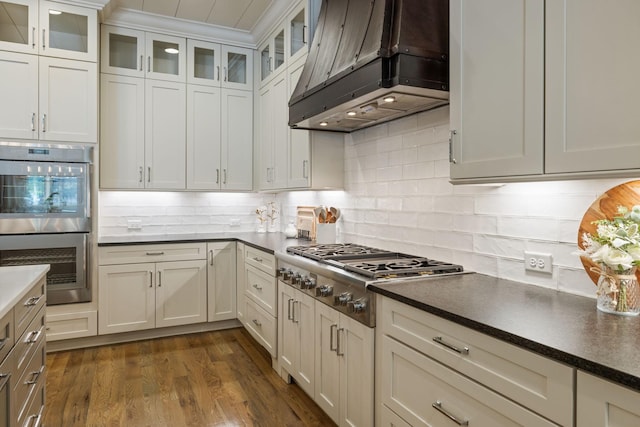 8524 Heirloom Blvd, College Grove, TN 37046 - kitchen with ventilation hood, appliances with stainless steel finishes, dark countertops, backsplash, and dark wood finished floors