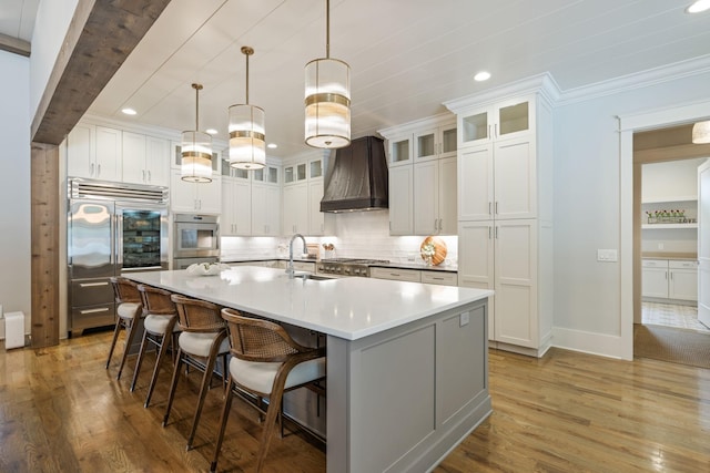 8524 Heirloom Blvd, College Grove, TN 37046 - kitchen featuring appliances with stainless steel finishes, tasteful backsplash, light wood-style flooring, custom range hood, and a large island
