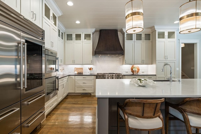 8524 Heirloom Blvd, College Grove, TN 37046 - kitchen featuring appliances with stainless steel finishes, recessed lighting, premium range hood, a kitchen bar, and dark wood-style floors