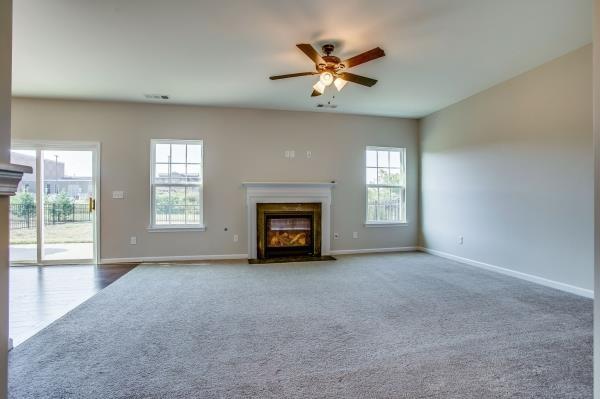 107 Clavie Crew Ln, Spring Hill, TN 37174 - unfurnished living room with a glass covered fireplace, carpet floors, and a ceiling fan