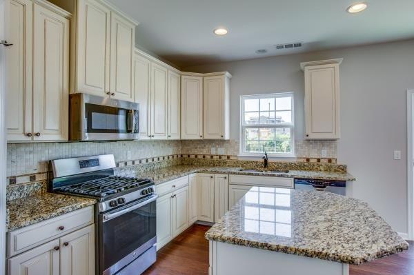 107 Clavie Crew Ln, Spring Hill, TN 37174 - kitchen with stainless steel appliances, light stone countertops, decorative backsplash, a center island, and recessed lighting