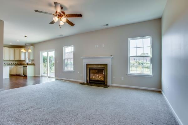 107 Clavie Crew Ln, Spring Hill, TN 37174 - unfurnished living room featuring carpet flooring, a fireplace with flush hearth, and ceiling fan