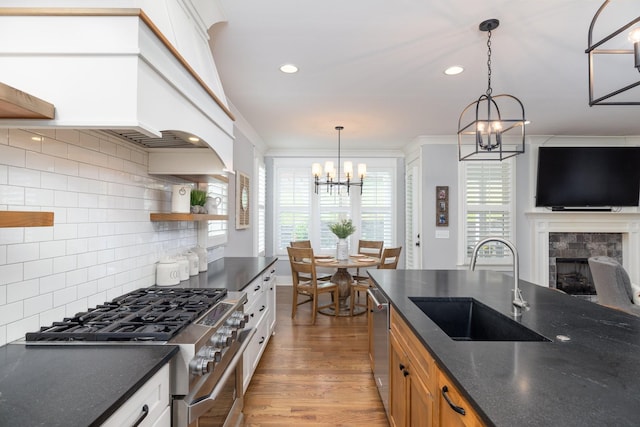 212 Rich Cir, Franklin, TN 37064 - kitchen featuring a chandelier, stainless steel appliances, a tile fireplace, backsplash, and light wood-style flooring
