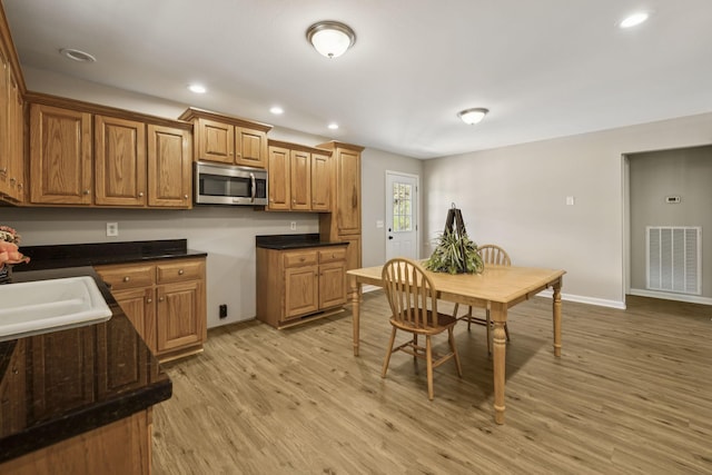 92 Defeated Creek Hwy, Carthage, TN 37030 - kitchen featuring light wood finished floors, stainless steel microwave, brown cabinetry, dark countertops, and recessed lighting