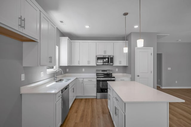 209 E Quail Hollow Way, Dickson, TN 37055 - kitchen with appliances with stainless steel finishes, light wood finished floors, light countertops, a kitchen island, and white cabinetry