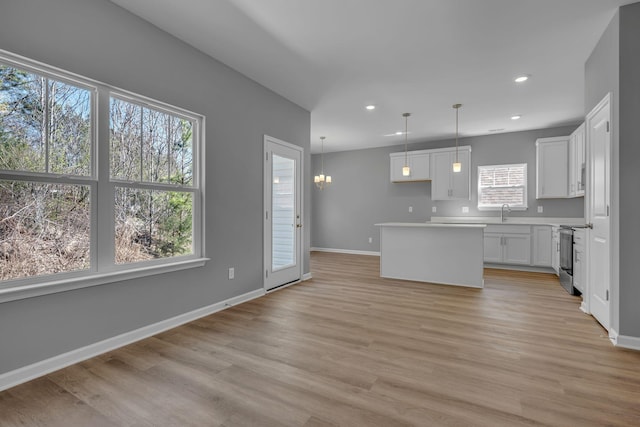 209 E Quail Hollow Way, Dickson, TN 37055 - kitchen featuring a center island, white cabinetry, light wood-type flooring, decorative light fixtures, and stainless steel electric range