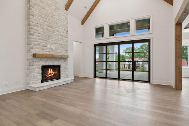 512 Wilson Pike, Brentwood, TN 37027 - unfurnished living room featuring high vaulted ceiling, beamed ceiling, a stone fireplace, and wood finished floors