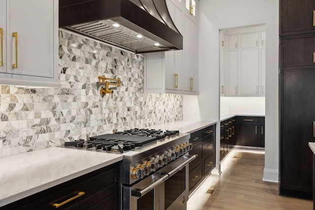 512 Wilson Pike, Brentwood, TN 37027 - kitchen with wall chimney exhaust hood, range with two ovens, light countertops, white cabinetry, and decorative backsplash