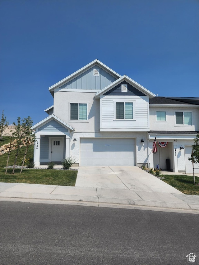 9786 N Aaron Ave E Unit 221, Eagle Mountain, UT 84005 - view of front of house with board and batten siding, an attached garage, a front lawn, and concrete driveway