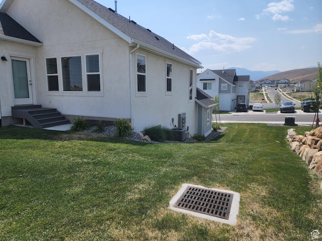 9786 N Aaron Ave E Unit 221, Eagle Mountain, UT 84005 - view of side of home with a mountain view, entry steps, a yard, stucco siding, and roof with shingles